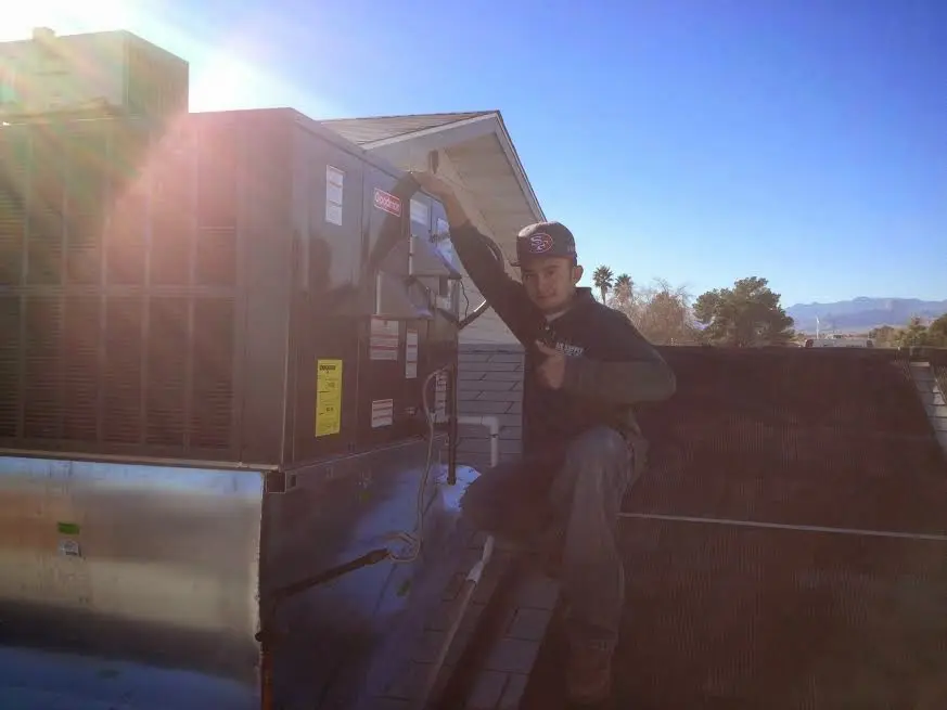 HVAC technician performing AC Tune-Up on a rooftop unit in Lacombe